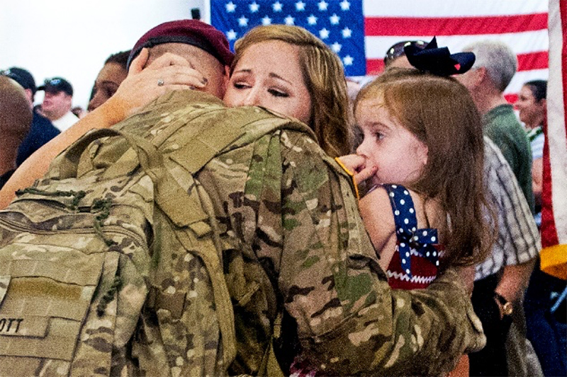 Return soldier hugging his wife and daughter