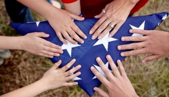 Multiple hands on folded U.S. flag